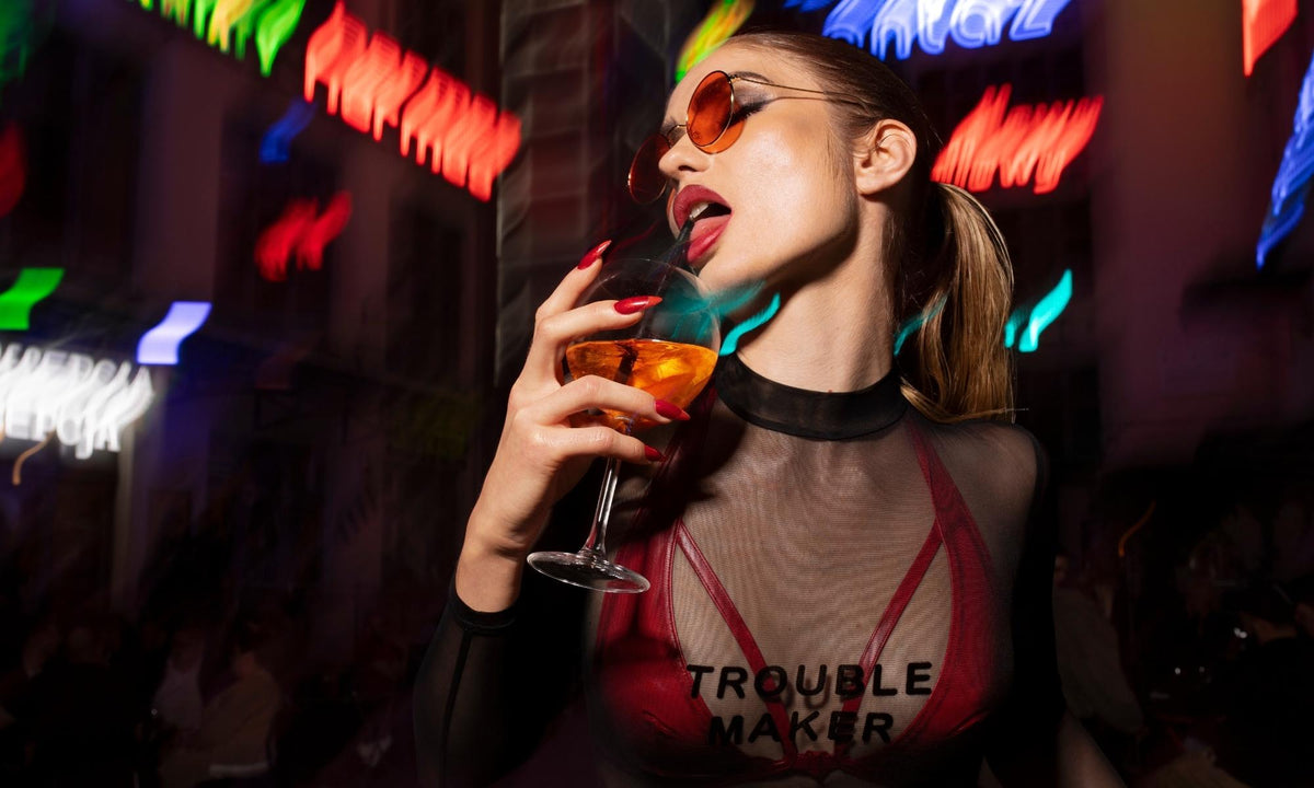 Frau in transparenter Bluse und Cocktail in Nachtkulisse